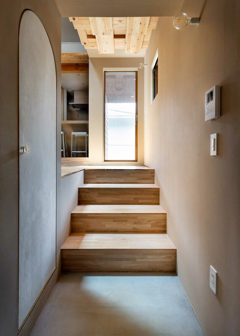 hallway view looking at four wood stairs up to glass door