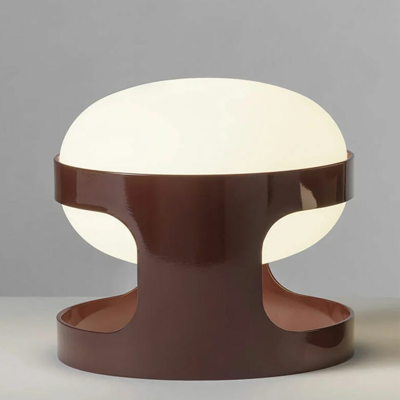 A modern table lamp with a glossy brown base and a large, rounded white lampshade, perfect for adding warmth and style to your space this Valentine's Day, set against a plain gray background.
